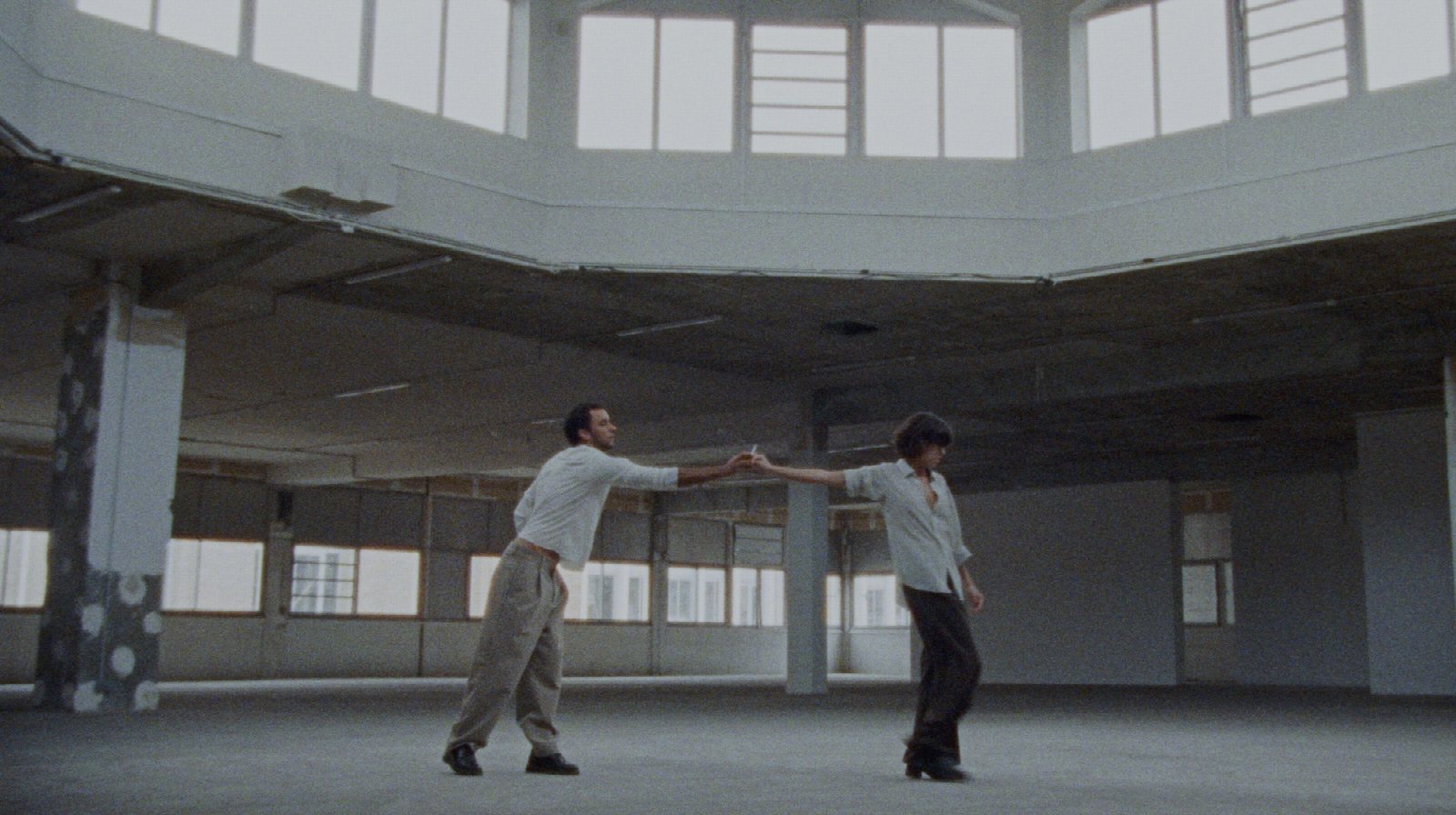 Two dancers share a cigarette in a vast, light-filled former POUSH space, captured on 16mm.
